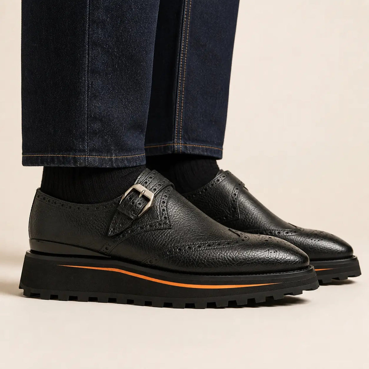 Black brogued single-buckle monk shoes with lug sole on foot