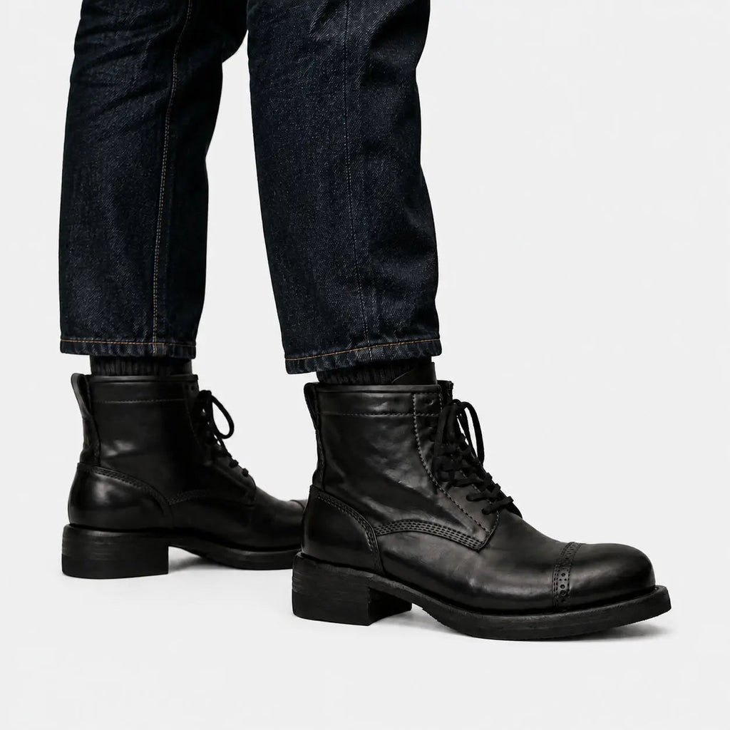 Black cap-toe combat boots worn with raw indigo denim