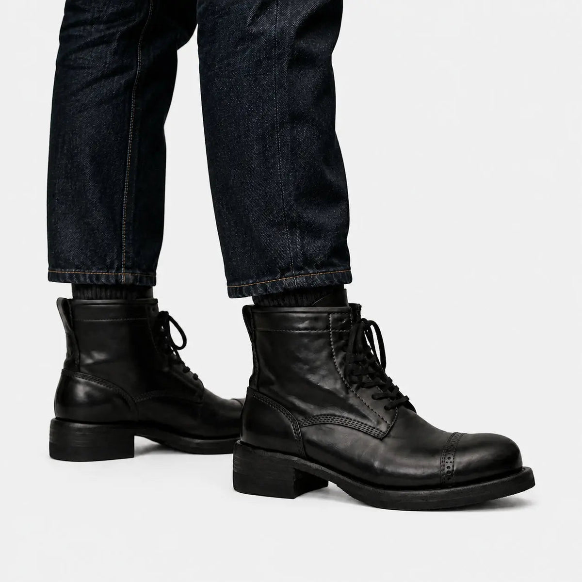 Black cap-toe combat boots worn with raw indigo denim