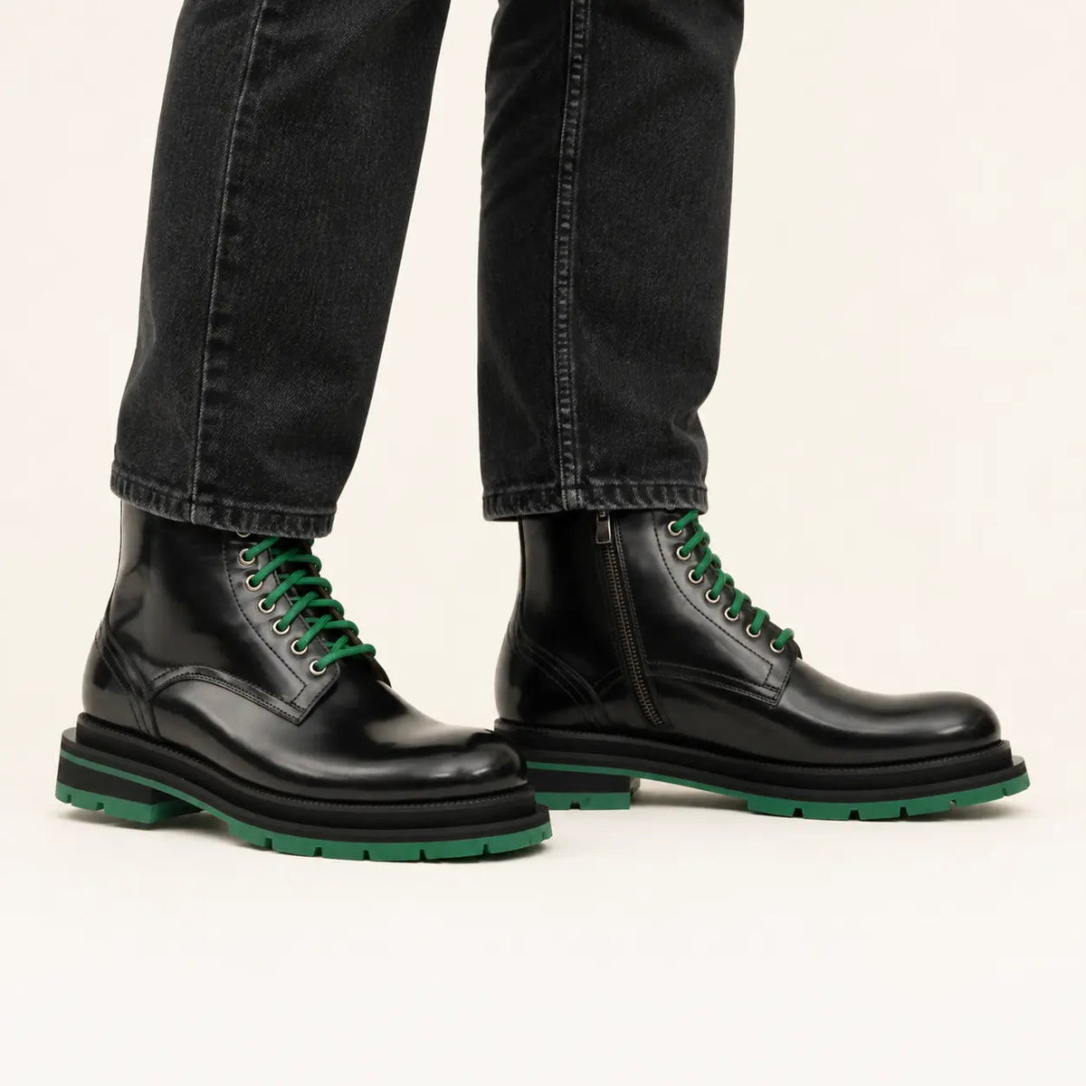 Black lace-up boots with green sole on-foot studio photo