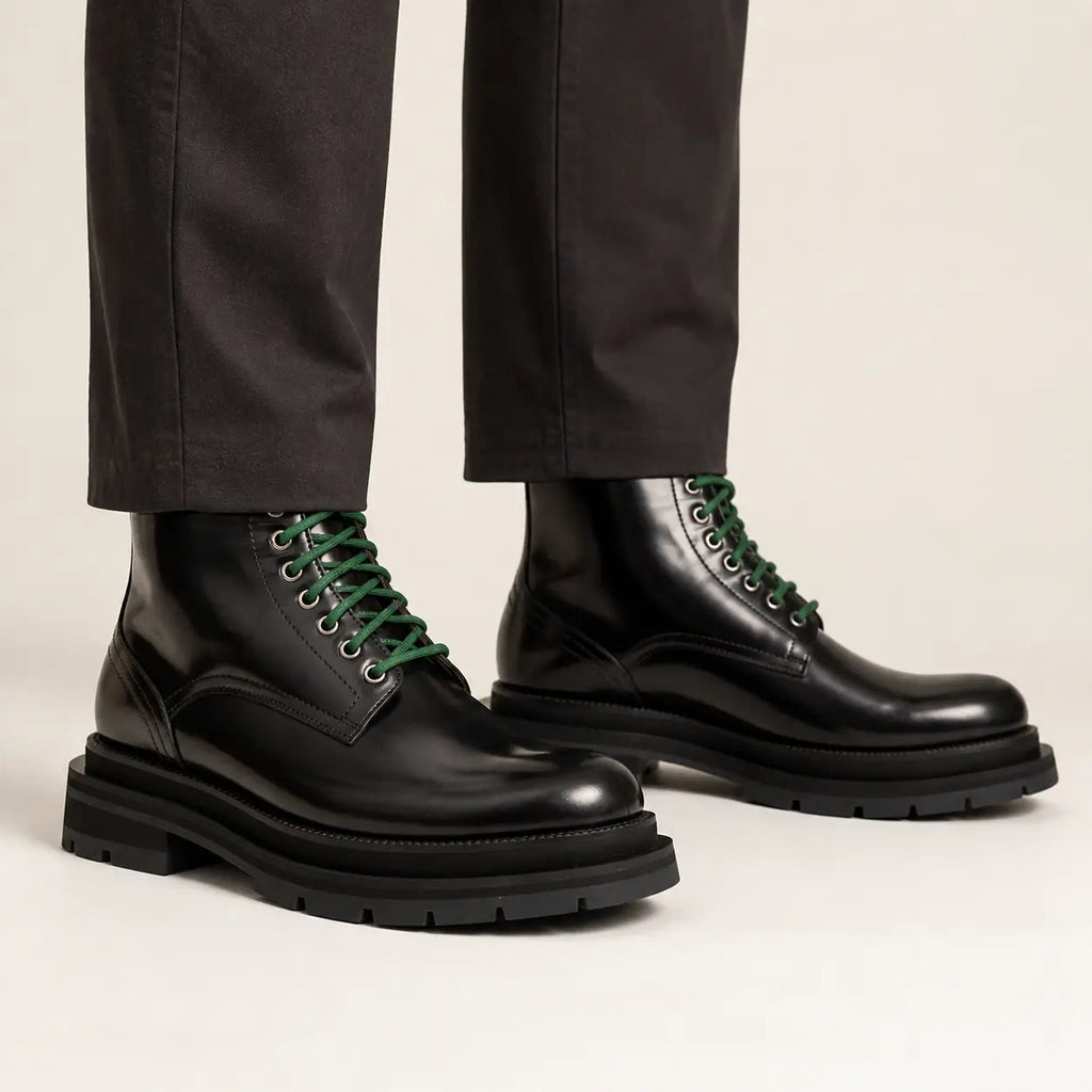 Black leather boots with green laces on-foot studio photo