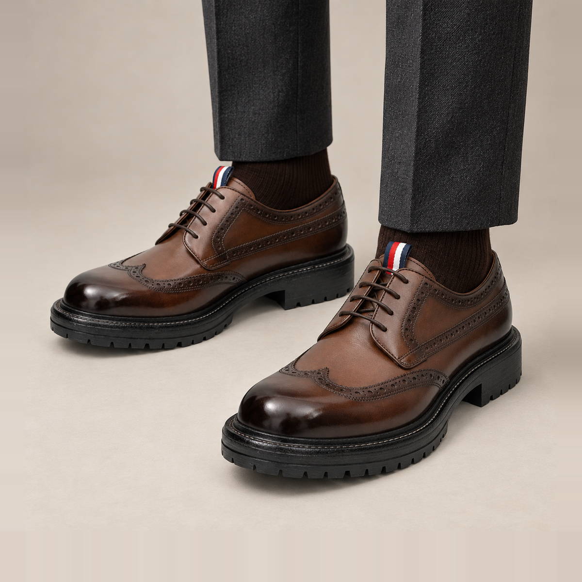 Brown Wingtip Derby Shoes with Medallion and Tongue Tab — on-foot studio view