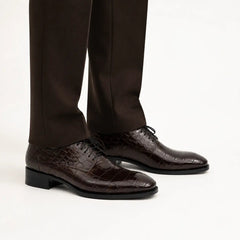 Dark brown crocodile-textured Derby shoes on foot