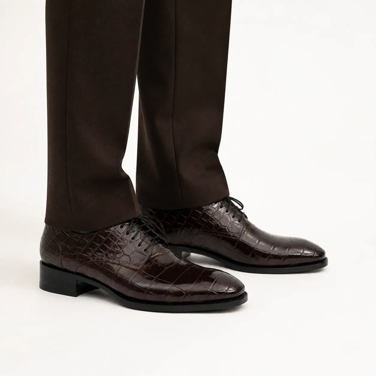 Dark brown crocodile-textured Derby shoes on foot