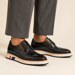 Dark navy and brown brogue Derby with contrast sole worn with warm-gray wide-leg trousers