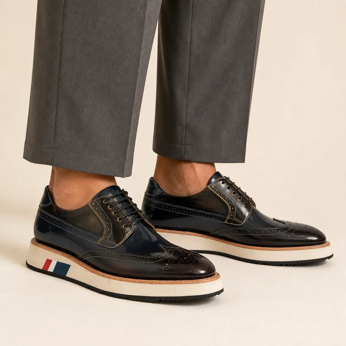 Dark navy and brown brogue Derby with contrast sole worn with warm-gray wide-leg trousers